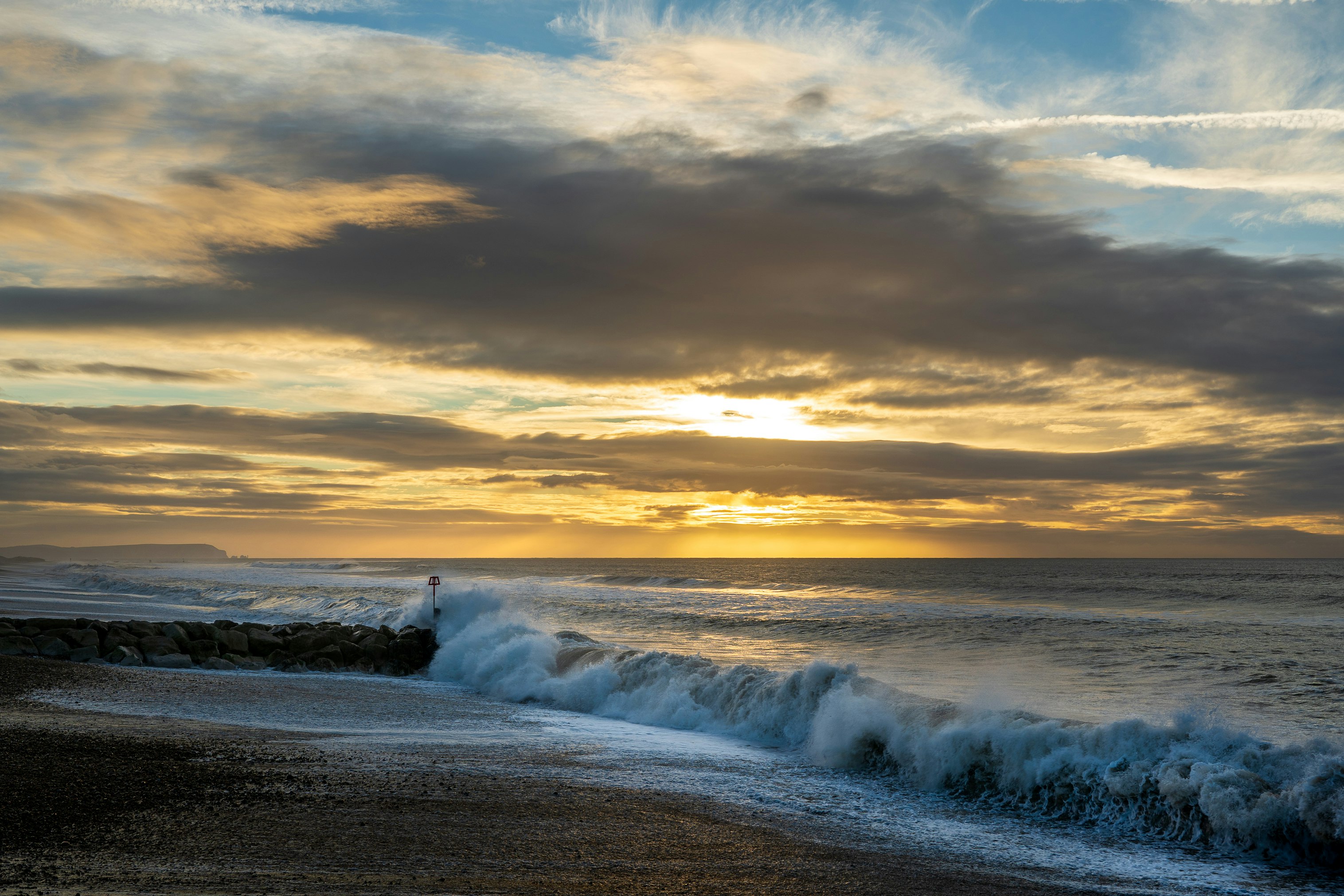 ocean waves crashing on shore during sunset